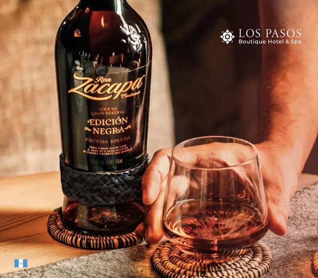A bottle of Ron Zacapa and a glass of rum on woven coasters